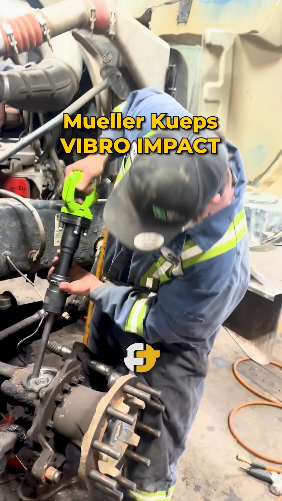 Worker using the Mueller-Kueps Vibro Impact tool on a heavy-duty vehicle component.