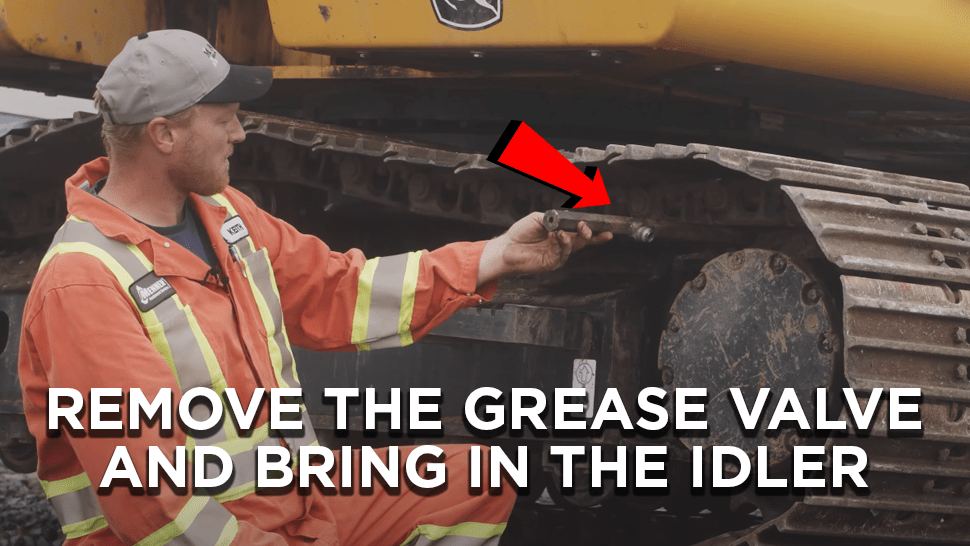Pointing out where to remove the grease valve in an excavator track