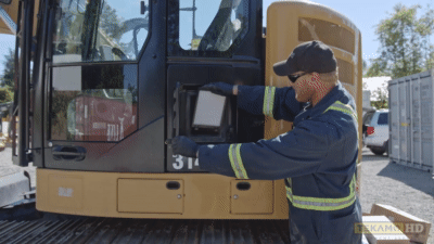 Heavy-duty mechanic installs a new cabin air filter on a Cat 314E excavator.