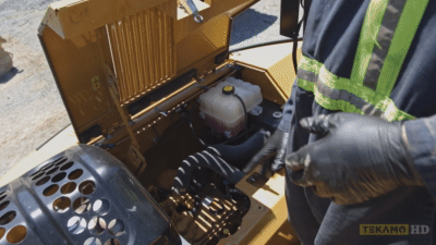 Heavy duty mechanic shows where to find the engine oil fill port on an excavator