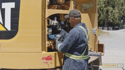Heavy equipment service technician lubricates the oil filter casing