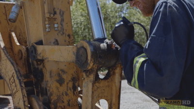 Heavy duty mechanic filling a cavity with grease on an excavator