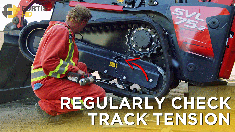 Heavy-duty mechanic adjusts the tension of a rubber track on a Kubota SVL 75-2 CTL