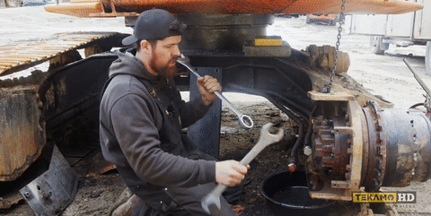 A heavy-duty mechanic shows the double wrench method with two combination wrenches.