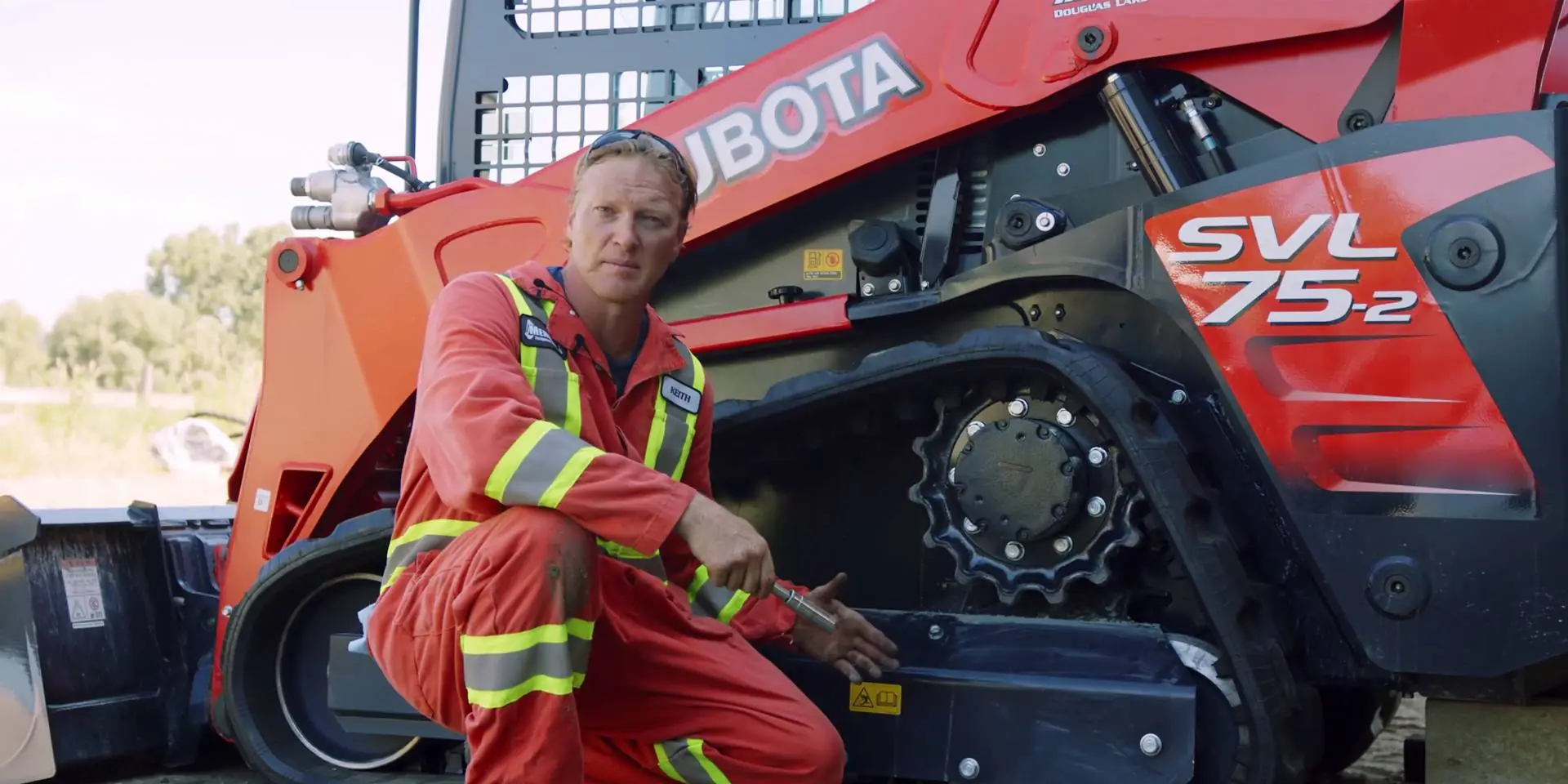 Keith crouched in front of Kubota SVL75-2 about to change the track