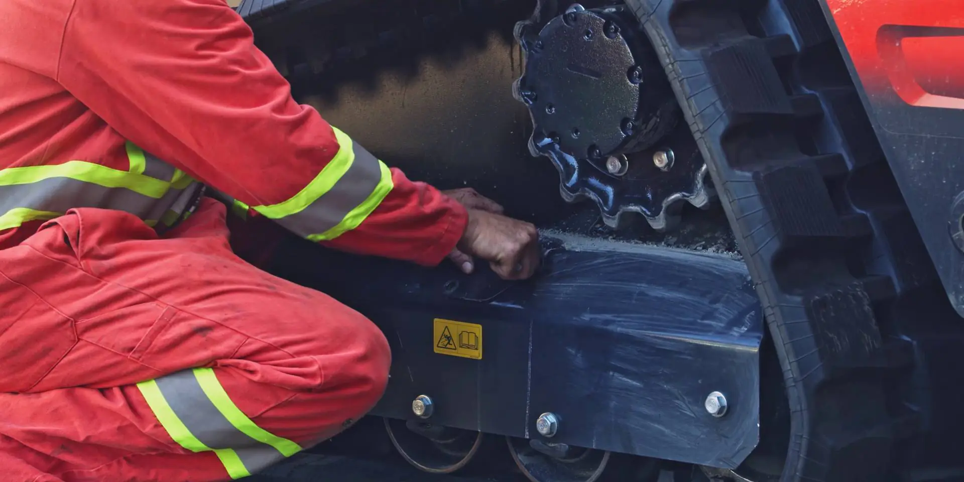 mechnic opens the grease valve on a compact track loader