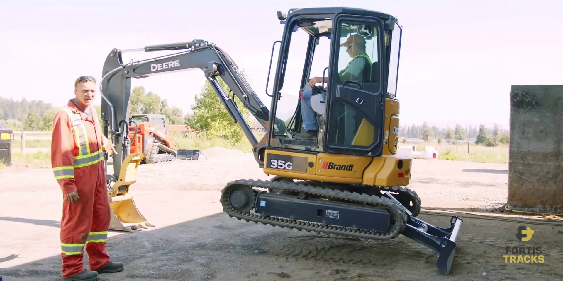 Heavy duty equipment operator using the blade and bucket to lift a mini excavator off it's tracks