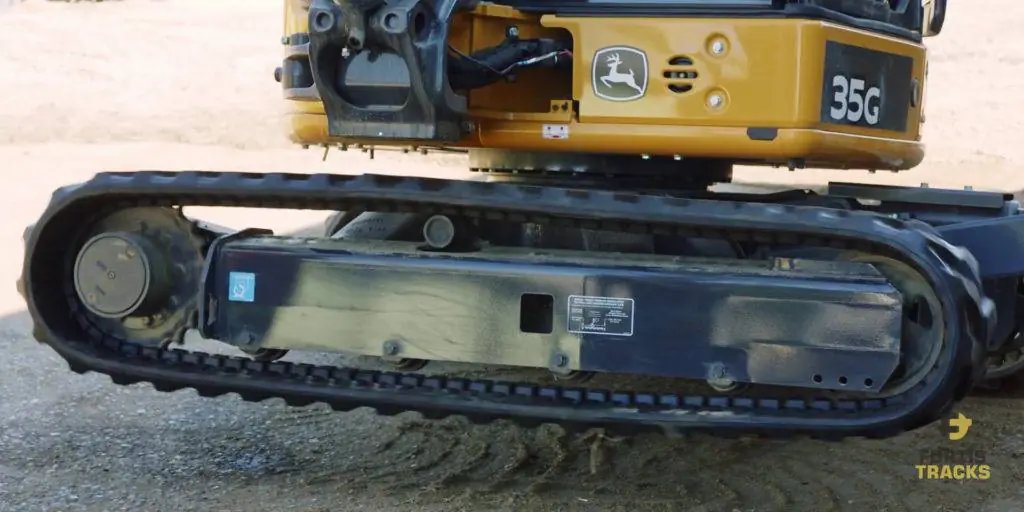 A mini excavator with one of it's tracks lifted in the air