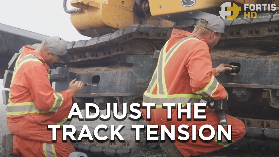 A heavy-duty mechanic adjusts the track tension of a John Deere 135G Excavator.