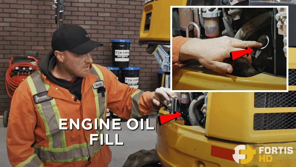 A heavy-duty mechanic is beside the backside compartment of a 17G Mini Excavator. An overlay arrow shows the location of the engine oil fill.