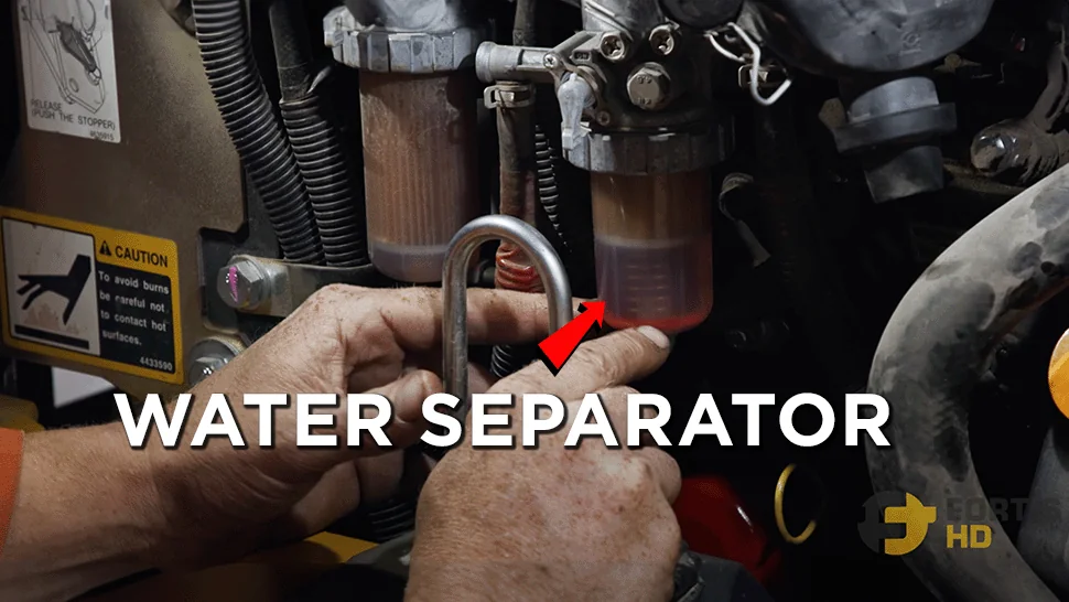 A heavy-duty mechanic points at the water separator on a John Deere 17G Mini Excavator.