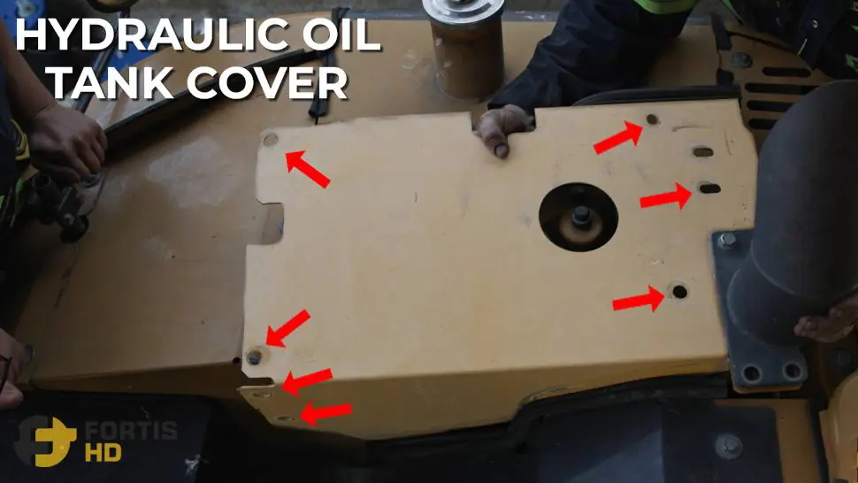 A heavy-duty mechanic lifts the hydraulic oil tank top cover of a John Deere 85G Excavator.