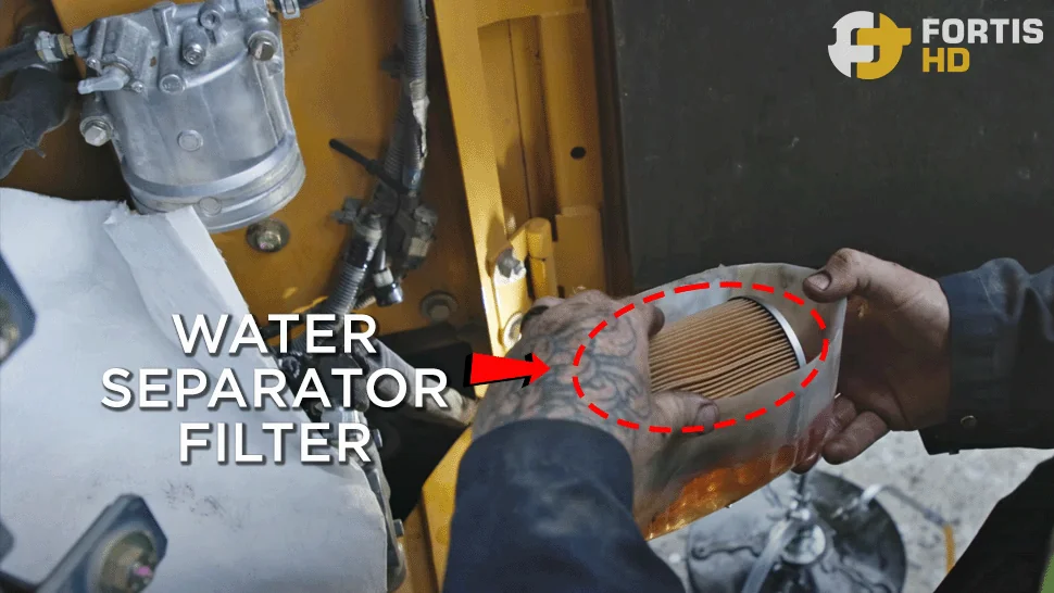 A heavy-duty mechanic removes a water separator filter on a John Deere 85G Excavator.