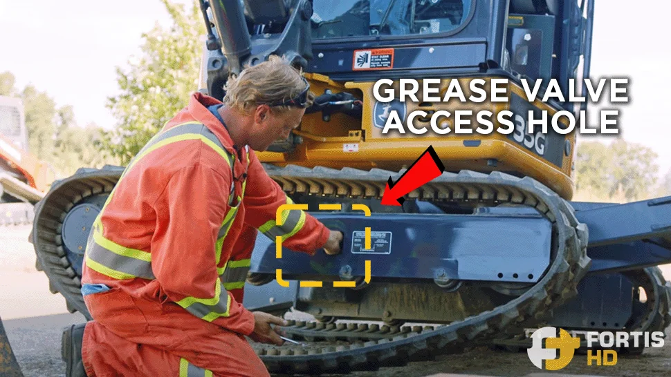 An arrow shows the location of the grease valve access hole on a John Deere 35G mini excavator.