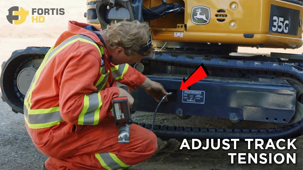 Heavy-duty mechanic pumps grease to adjust the track tension on a John Deere 35G mini excavator.