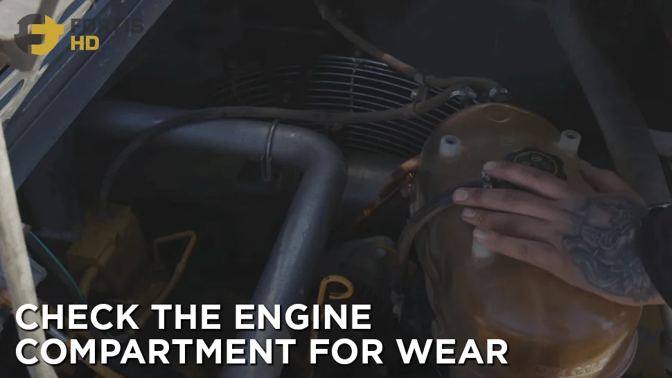 Heavy-duty mechanic uses a flashlight to check the engine on a John Deere 250G LC Excavator.