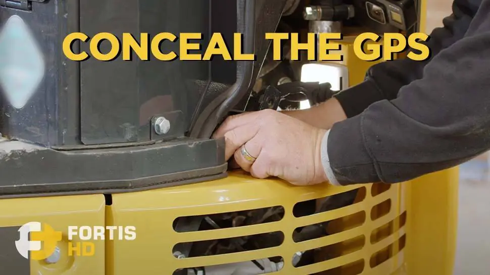 A heavy equipment operator conceals a GPS tracker he installed on a John Deere 26G.