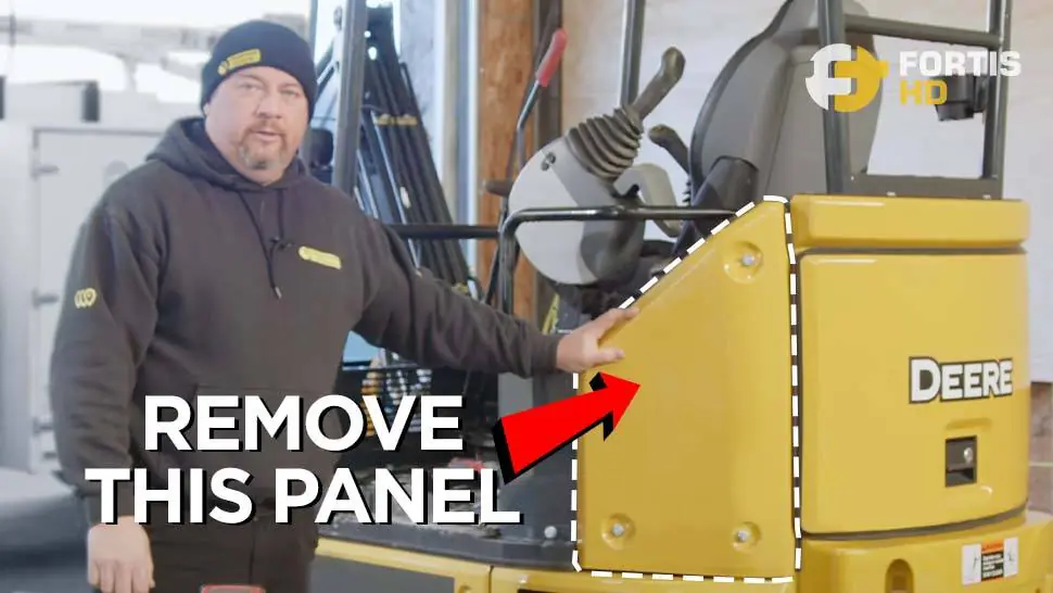 An arrow points at the panel you must remove to install a GPS tracker on a John Deere 26G.